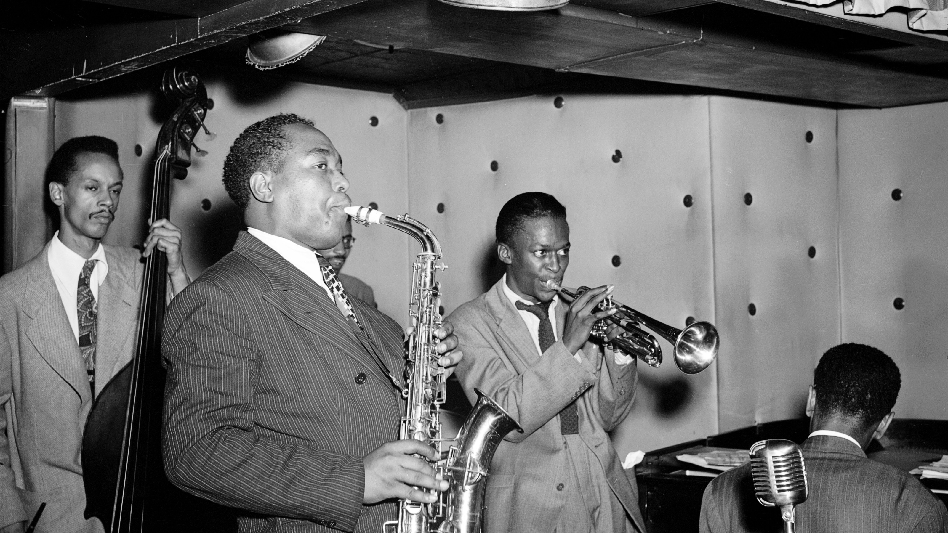 A group of artistic men in suits playing saxophones with genius skill.