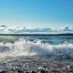 A beach along the Great Lakes with waves crashing over rocks and sand.